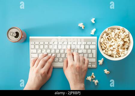 Filme mit Popcorn auf blauem Hintergrund ansehen, flach liegend. Stockfoto