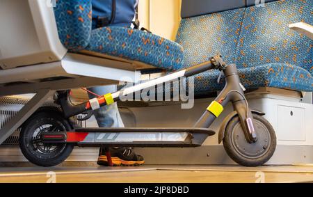 Ein Passagier im Zug fährt mit einem Elektroroller Stockfoto