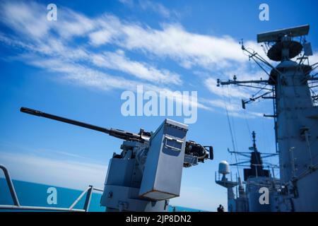 Farbbild eines automatisierten Maschinengewehrs auf dem Deck eines Militärschiffs auf See. Stockfoto