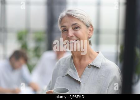 Nahaufnahme reife Frau hält eine Tasse im Büro Stockfoto