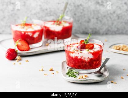 Vegetarisches Fruchtcreme-Dessert mit Erdbeerpüree, Joghurt und Müsli in Glasschüsseln. Hausgemachtes gesundes, sauberes Lebensmittelkonzept. Speicherplatz kopieren. Stockfoto