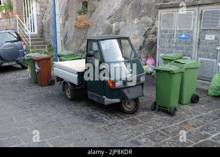 Ein leichtes Nutzfahrzeug aus dem Jahr Ape50, hergestellt vom italienischen Kraftfahrzeughersteller Piaggio, das in Sorrent (Italien) unter Abfallbehältern geparkt ist. Stockfoto