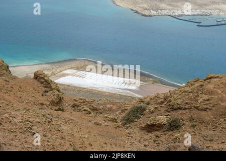 Salinas del Río im Vordergrund mit Isla de La Graciosa im Hintergrund Stockfoto