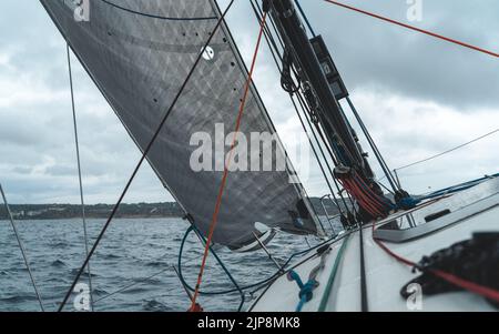 Segelyacht im Meer. Nahaufnahme von Deck, Mast und Segeln mit bewölktem Himmel. Stockfoto