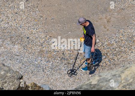 Ein Mann, ein Metalldetektor, der an einem Strand in Cornwall in Großbritannien sucht. Stockfoto