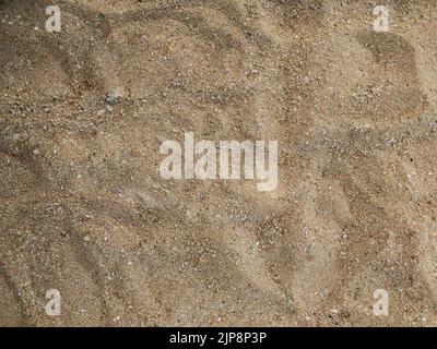 Draufsicht Sandstrand mit natürlichem Licht, füllen Sie den Rahmen mit Sandstrand, Oberfläche mit Volumen, flache Lay-Vorlage mit Leerraum für Kopie und Design. Stockfoto