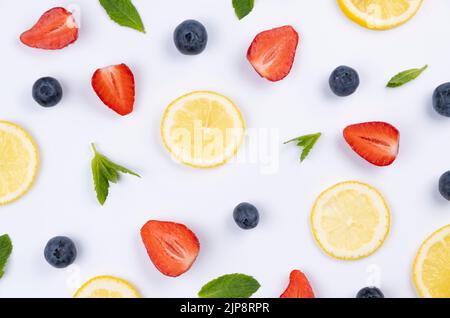 Hintergrund von Heidelbeeren, Erdbeeren, Zitronenscheiben und Minzblättern auf weißem Hintergrund - das Konzept einer gesunden Ernährung. Sommer hellen Hintergrund, Food-Design. Hohe Qualität Stockfoto