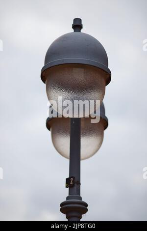 Eine vertikale Aufnahme einer Straßenlampe mit runden Glühbirnen auf weißem Hintergrund Stockfoto