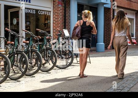 Dorking, Surrey Hills, London, Großbritannien, August 14 2022, zwei junge Frauen, die an einem E-Bike-Verleih oder -Verleih vorbeilaufen Stockfoto