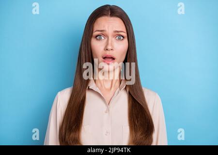 Foto von wunderschönen Angst hübsche Frau mit langen Frisur gekleidet beige Bluse starrte auf Kamera isoliert auf blauem Hintergrund Stockfoto