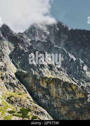 Zerklüftete felsige Gipfel in der Hohen Tatra, Slowakei, mit Wolken um Granitklippen und dramatischer alpiner Wildnislandschaft. Stockfoto