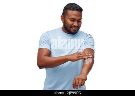 Glücklicher afrikanischer Mann, der Feuchtigkeitscreme auf seine Hand anwendet Stockfoto