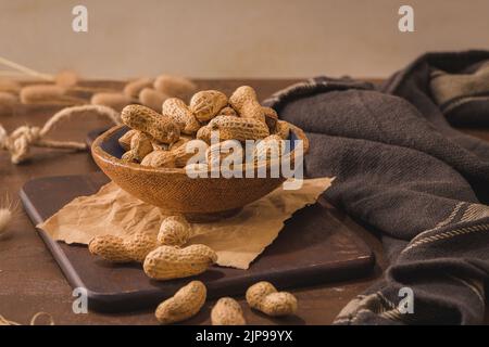 Erdnüsse in einer Keramikschale auf einer rustikalen Küchenarbeitspüle. Stockfoto