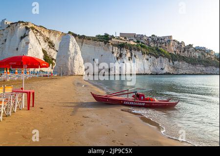 Vieste, Foggia, Italien 26 Juni 2021 Scialara, ein sandiger Sonnenaufgangsstrand und im Hintergrund auf kalkigen Felsen die Altstadt von Vieste und der Monolith Pizzomunno Stockfoto