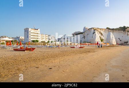 Vieste, Foggia, Italien 26 Juni 2021 Scialara, ein sandiger Sonnenaufgangsstrand und im Hintergrund auf kalkigen Felsen die Altstadt von Vieste und der Monolith Pizzomunno Stockfoto