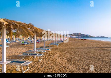 Vieste, Foggia, Italien 26 Juni 2021 Scialara, ein sandiger Sonnenaufgangsstrand und im Hintergrund auf kalkigen Felsen die Altstadt von Vieste und der Monolith Pizzomunno Stockfoto