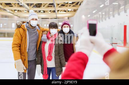 Freunde in Masken fotografieren auf der Eisbahn Stockfoto