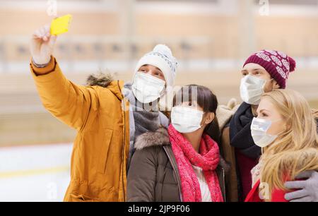 Freunde in Masken machen Selfie auf der Eisbahn Stockfoto