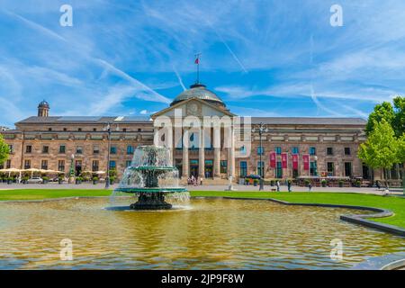 Schöner Blick auf den Haupteingang des Wiesbadener Kurhauses auf der Westseite mit einem Springbrunnen davor. Auf dem Portal des Gebäudes die Worte... Stockfoto