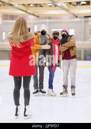 Freunde in Masken fotografieren auf der Eisbahn Stockfoto