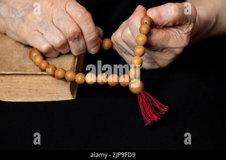 Alte Frau mit hölzernen Rosenkranz und bibel, Frau beten, beten, Glauben und Religion Stockfoto