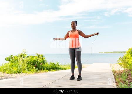 afrikanische Frau trainiert am Strand mit Springseil Stockfoto