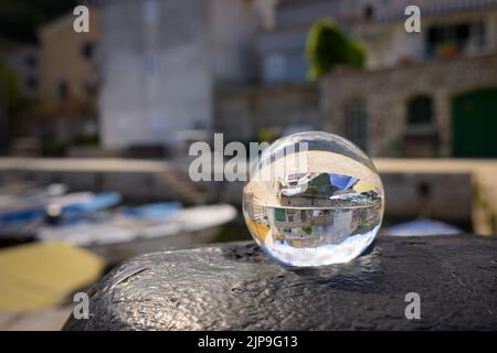 Glaskugel auf einem rostigen Poller, Hafen von Valun (Kroatien), sonniger Tag im Frühling Stockfoto
