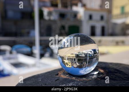 Glaskugel auf einem rostigen Poller, Hafen von Valun (Kroatien), sonniger Tag im Frühling Stockfoto