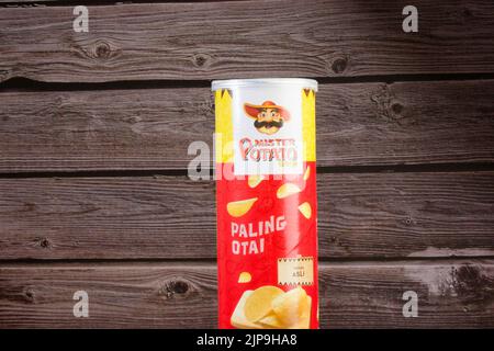 Eine Plastikdose von Mister Potato Delicious Spicy Chips vor Holzhintergrund Stockfoto