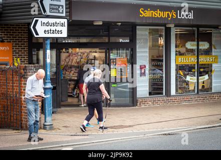 Billingshurst, West Sussex, Großbritannien, 16. August 2022. Eine Frau, die mit einem Gehstock und mit Mobilitätsprobleme unterwegs ist, geht an einem Sainsbury's Supermarkt in Billingshurst, West Sussex, Großbritannien, vorbei. In einem Bericht, der heute vom britischen Superstore veröffentlicht wurde, wurde festgestellt, dass Sainsbury's der am meisten beklagte Supermarkt in Großbritannien für behinderte Käufer ist. Stockfoto