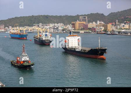 Hafen von Kaohsiung (高雄港), größter Hafen in Taiwan, mit Frachtgut, Militärschiffen, Docks und Schleppschiffen Stockfoto