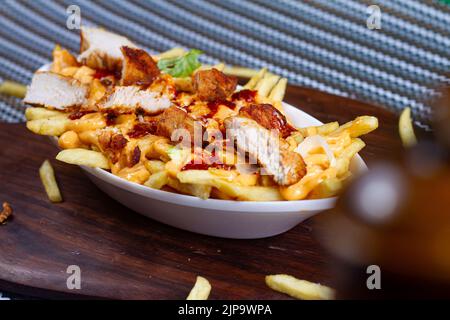 Gericht mit KITSCHIGEN TIKKA POMMES im Café-Restaurant. Amerikanisches Fast-Food-Gericht, bestehend aus pommes Frites mit Käse. Stockfoto