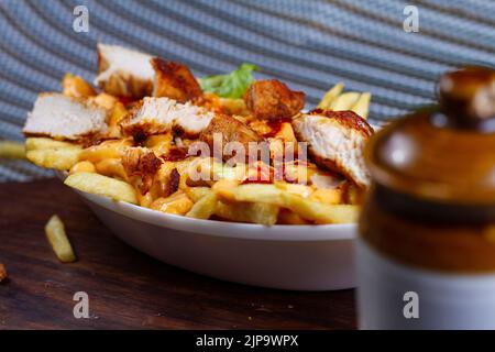 Gericht mit KITSCHIGEN TIKKA POMMES im Café-Restaurant. Amerikanisches Fast-Food-Gericht, bestehend aus pommes Frites mit Käse. Stockfoto