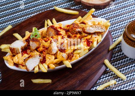 Gericht mit KITSCHIGEN TIKKA POMMES im Café-Restaurant. Amerikanisches Fast-Food-Gericht, bestehend aus pommes Frites mit Käse. Stockfoto