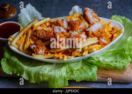 Gericht mit kitschigen Fisch, Popcorn-Pommes im Café-Restaurant. Amerikanisches Fast-Food-Gericht, bestehend aus pommes Frites mit Käse. Stockfoto