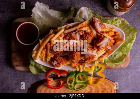 Gericht mit kitschigen Fisch, Popcorn-Pommes im Café-Restaurant. Amerikanisches Fast-Food-Gericht, bestehend aus pommes Frites mit Käse. Stockfoto