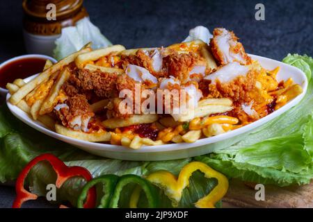 Gericht mit kitschigen Fisch, Popcorn-Pommes im Café-Restaurant. Amerikanisches Fast-Food-Gericht, bestehend aus pommes Frites mit Käse. Stockfoto