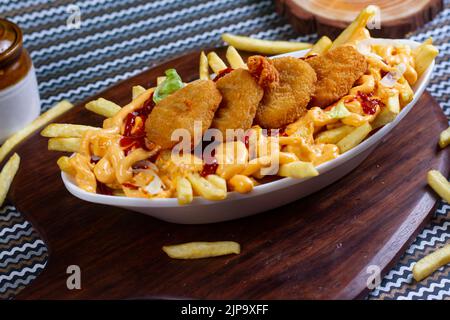 Gericht mit KITSCHIGEN NUGGET POMMES im Café-Restaurant. Amerikanisches Fast-Food-Gericht, bestehend aus pommes Frites mit Käse. Stockfoto