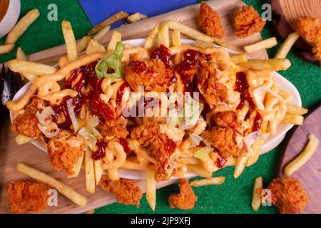 Gericht mit KITSCHIGEN POPCORN-POMMES im Café-Restaurant. Amerikanisches Fast-Food-Gericht, bestehend aus pommes Frites mit Käse. Stockfoto