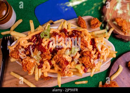 Gericht mit KITSCHIGEN POPCORN-POMMES im Café-Restaurant. Amerikanisches Fast-Food-Gericht, bestehend aus pommes Frites mit Käse. Stockfoto