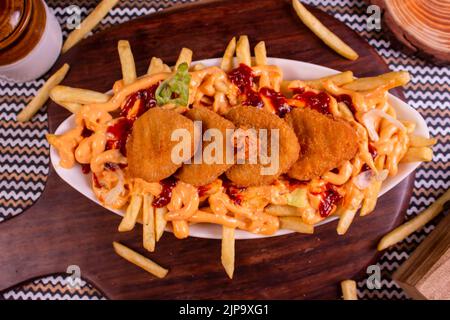 Gericht mit KITSCHIGEN NUGGET POMMES im Café-Restaurant. Amerikanisches Fast-Food-Gericht, bestehend aus pommes Frites mit Käse. Stockfoto