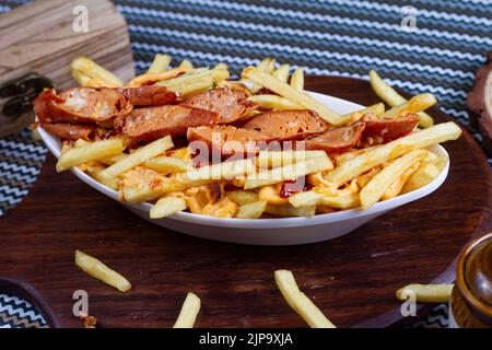 Gericht mit KITSCHIGEN WÜRSTCHEN IM Café-Restaurant. Amerikanisches Fast-Food-Gericht, bestehend aus pommes Frites mit Käse. Stockfoto