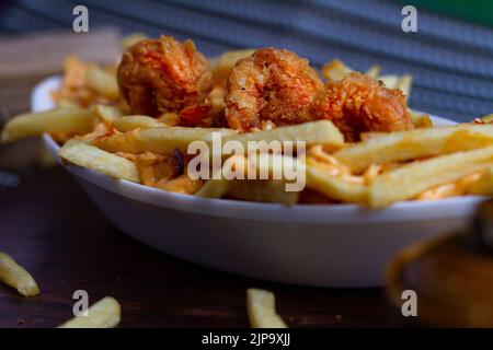 Gericht mit KITSCHIGEN GARNELEN-POMMES im Café-Restaurant. Amerikanisches Fast-Food-Gericht, bestehend aus pommes Frites mit Käse. Stockfoto