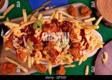 Gericht mit KITSCHIGEN POPCORN-POMMES im Café-Restaurant. Amerikanisches Fast-Food-Gericht, bestehend aus pommes Frites mit Käse. Stockfoto