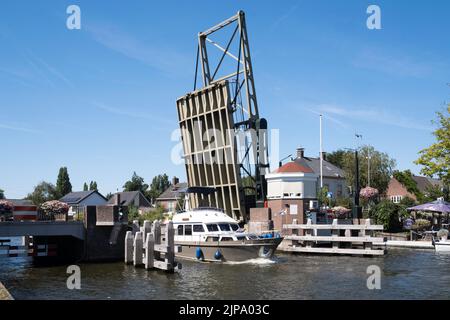 Das Boot fährt auf dem 'Oude Rijn' (Alter Rhein) unter der geöffneten Stahlzugbrücke im Dorf Koudekerk aan den Rijn, Niederlande Stockfoto