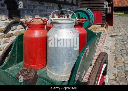 Antiker Handwagen, beladen mit alten Metall-Milchkrümmern / Milchdosen im Freilichtmuseum Bachten de Kupe im Sommer, Izenberge, Westflandern, Belgien Stockfoto