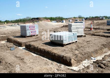 Paletten mit gestapelten Baumaterialien für Häuser – Windblöcke und Gräben für Fundamente auf einer Baustelle Stockfoto