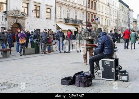 Ein Straßenmusiker spielt Gitarre auf dem Bürgersteig in der Grodzka-Straße in Krakau, Polen. Stockfoto