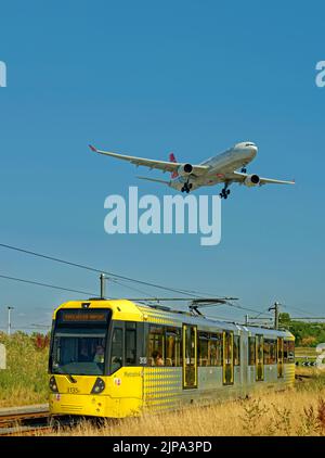 Die Straßenbahn von Manchester Metrolink und Flugzeuge von Turkish Airlines nähern sich der Haltestelle des Flughafens Manchester, Manchester, England. Stockfoto