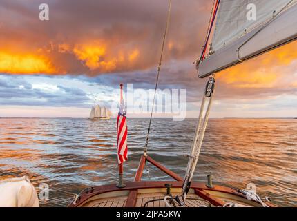 Segeln auf einem kleinen Segelboot mit Blick auf einen unglaublichen Sonnenuntergang und ferne Segelboot Stockfoto
